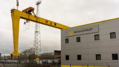 Getty Images إحدى الرافعات الجسرية الصفراء الشهيرة Harland & Wolff Samson وGoliath بالقرب من مدخل مبنى حوض بناء السفن Harland & Wolff. الخجول غائم. 