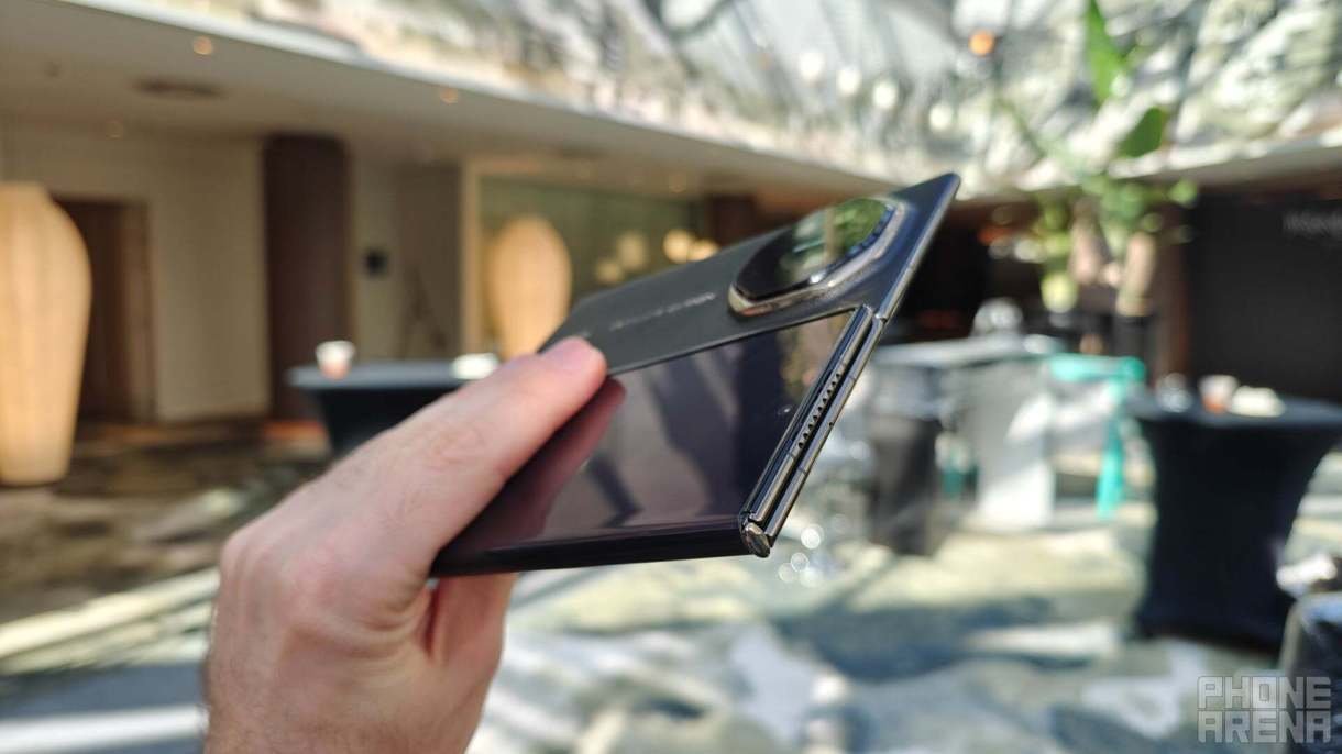 شخص يحمل هاتف Huawei Mate XT ثلاثي الطي بين يديه. 