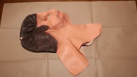 خدمة الادعاء التاج صورة أدلة للشرطة لقناع المطاط يسحب رأسك بالكامل. لدي شعر بني وبشرة فاتحة أسفل الرقبة ولحية خفيفة. 