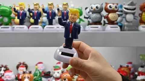 Getty Images يده تملك تمثالًا صغيرًا ترامب ، يوضح الرئيس الأمريكي في بدلة بحرية وربطة عنق حمراء ، بيد مرتفعة وفم مفتوح