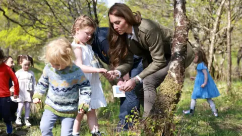 تفحص رويترز كاثرين الأغصان مع فتاة صغيرة بينما تمشي الفتيات الأخريات بين الأشجار