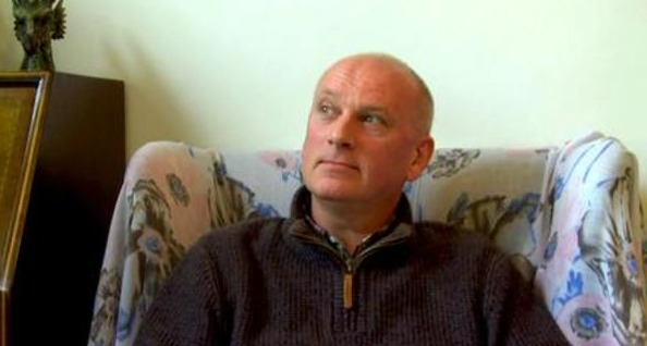 رجل يجلس على كرسي ، ينظر بعناية على يساره.