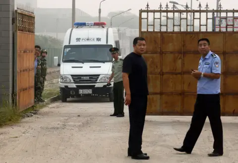 AFP/Getty Chinese police wait outside the Number Two prison after the release of dissident Wang Xiaoning in Beijing on August 31, 2012. The gates are rusted iron, the road grey and dusty. Several guards look at teh camera, a vehicle moving towards the one open gate.
