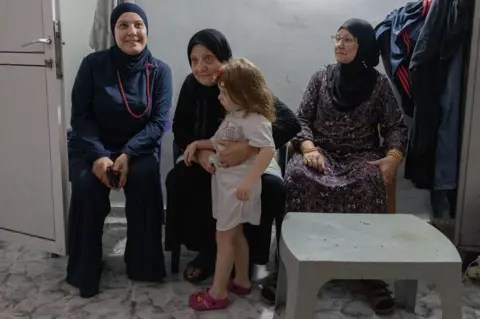 ثلاث نساء وفتاة صغيرة تجلس داخل غرفة آمنة.