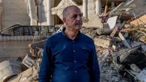 يقف عادل خاتيب على خلفية الأنقاض