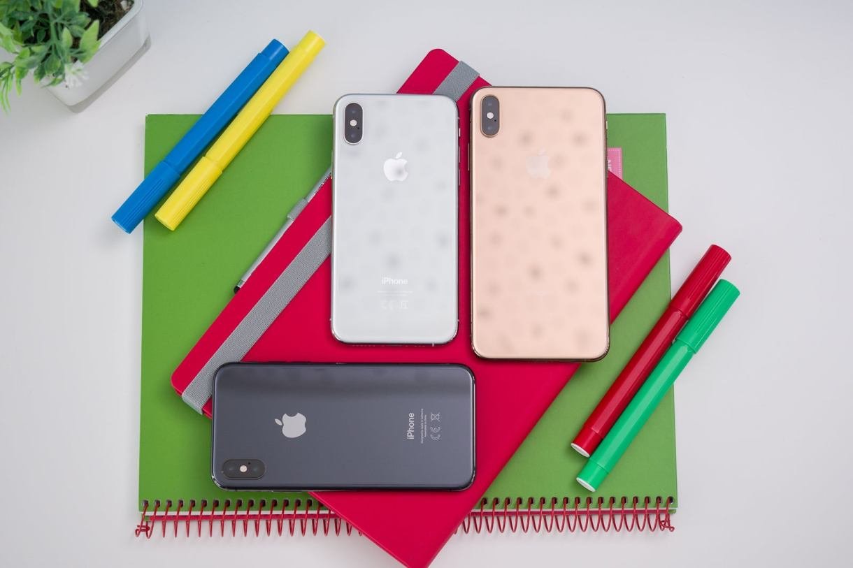 يتم عرض ثلاثة أجهزة iPhone من منظور من أعلى إلى أسفل على مجموعة من أجهزة الكمبيوتر المحمولة.