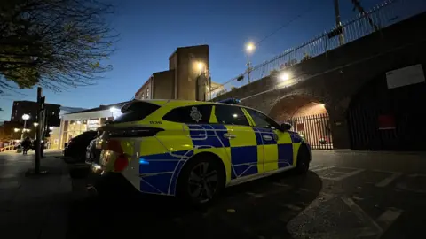 ستيوارت وودوارد/بي بي سي سيارة شرطة متوقفة خارج محطة سكة حديد تشيلمسفورد. الشمس تغرب في الصورة.